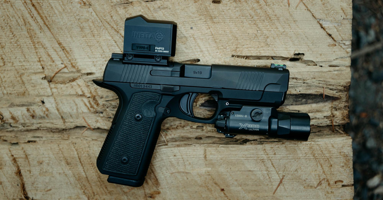 A black pistol with an INFITAG thermal optic and a SureFire X300U-B flashlight attached, resting on a textured wooden surface.