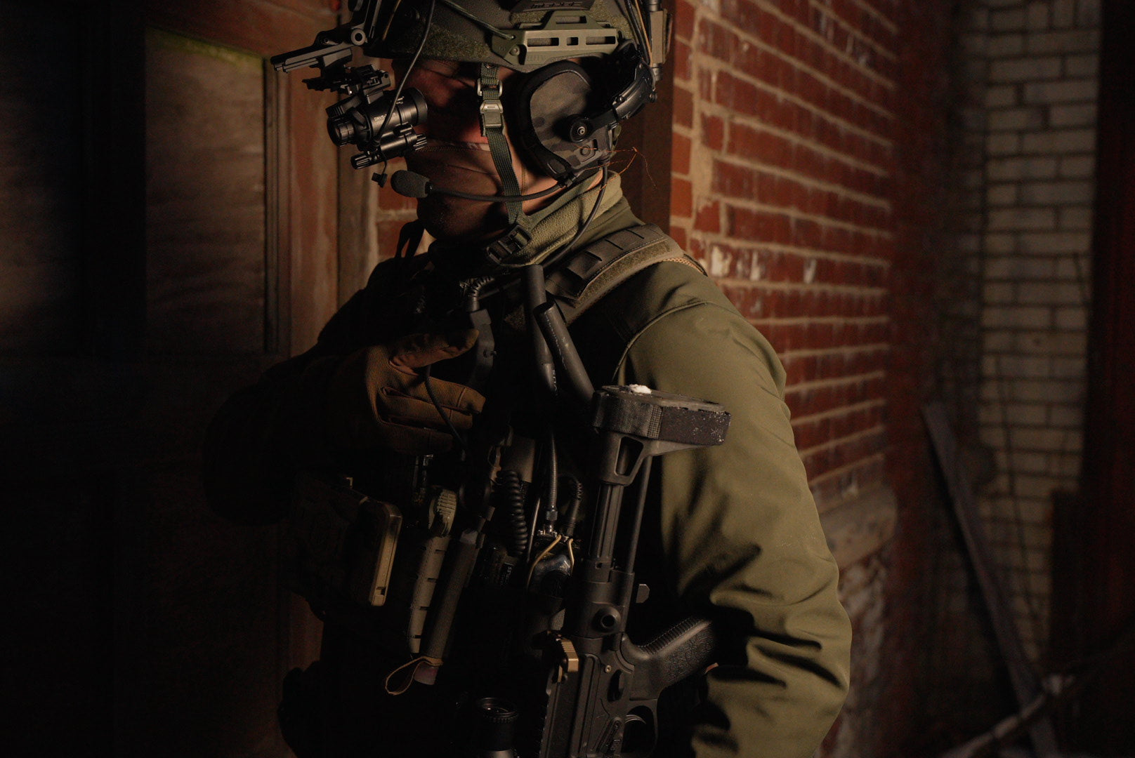Profile of a soldier in a dark brick interior wearing the INFITAC Night Vision Goggles DNVS-14 Pro and tactical gear