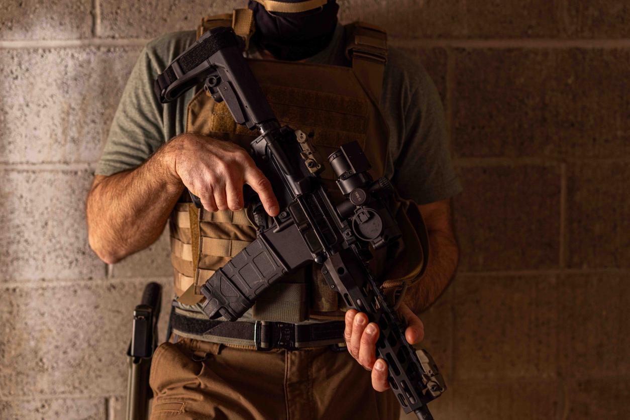 Tactical operator holding an AR rifle with mounted optic