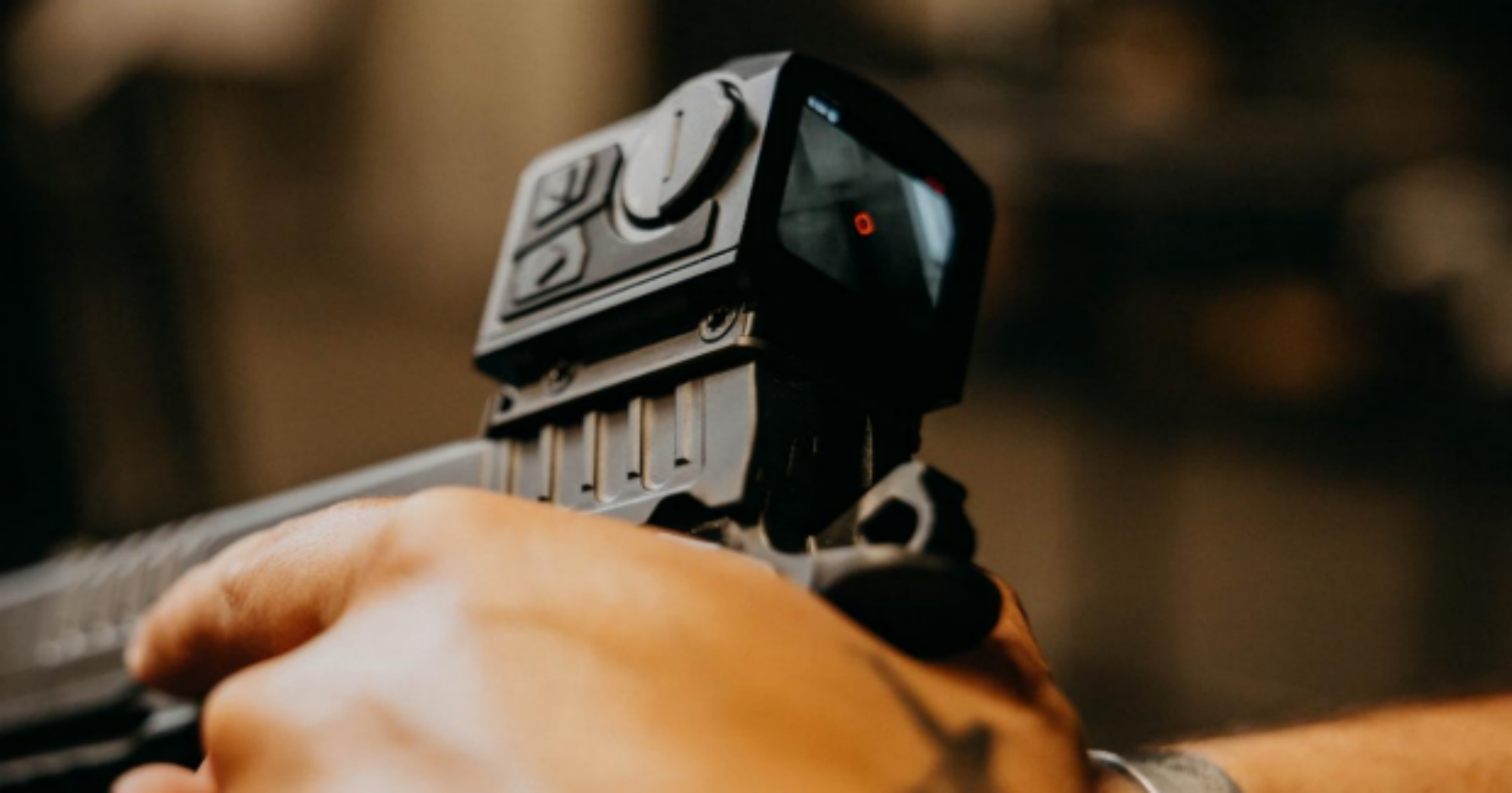 A close-up, over-the-shoulder view of a shooter aiming a firearm equipped with the InfiTac Fast Mini FMP13 thermal optic, focusing on the sight's digital display and red reticle